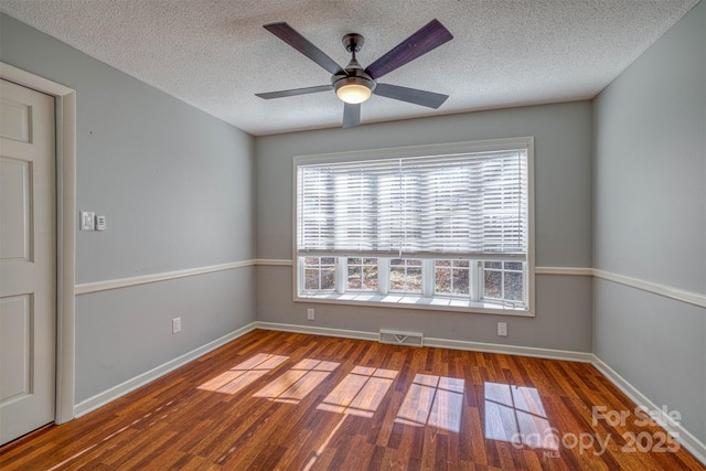 empty room featuring ceiling fan, wood-type flooring, and a textured ceiling