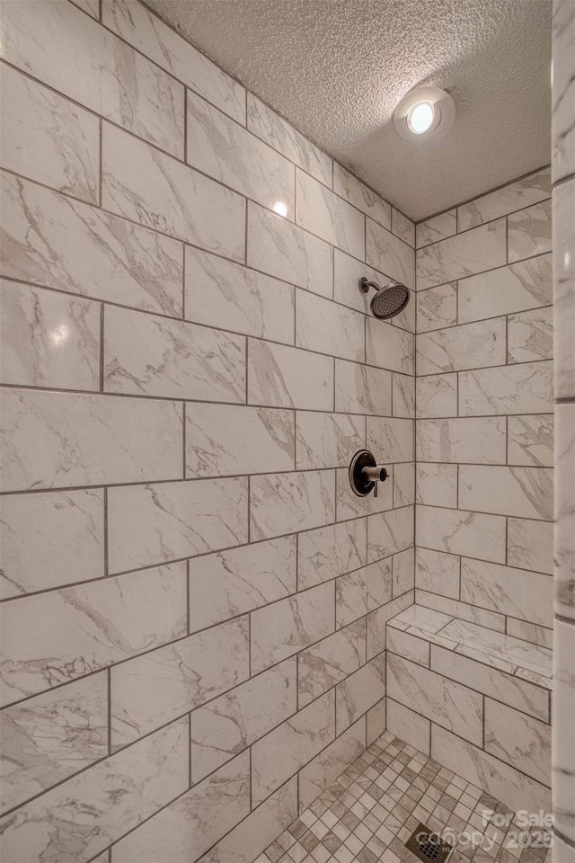 bathroom featuring tiled shower and a textured ceiling