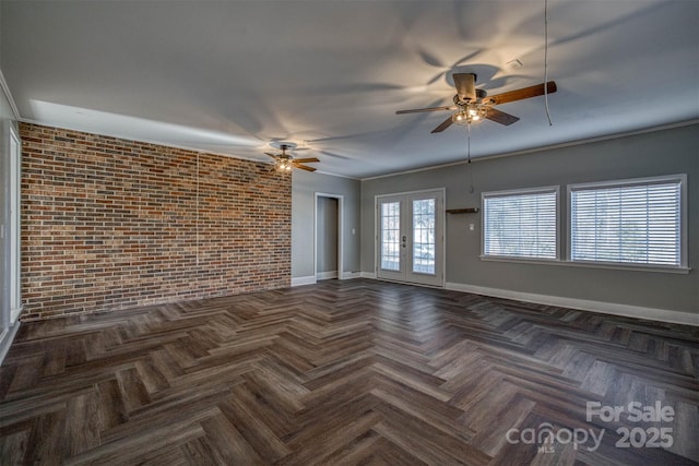 empty room with french doors, ornamental molding, dark parquet floors, ceiling fan, and brick wall