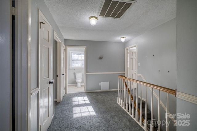 corridor featuring carpet flooring and a textured ceiling