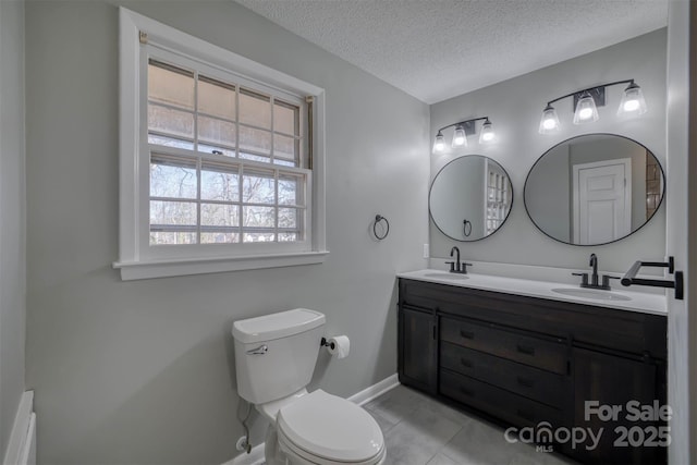 bathroom with tile patterned floors, vanity, toilet, and a textured ceiling