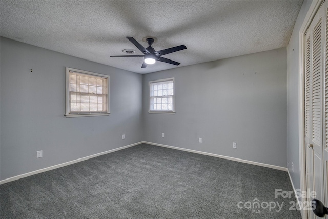 unfurnished bedroom featuring dark carpet, a textured ceiling, a closet, and ceiling fan