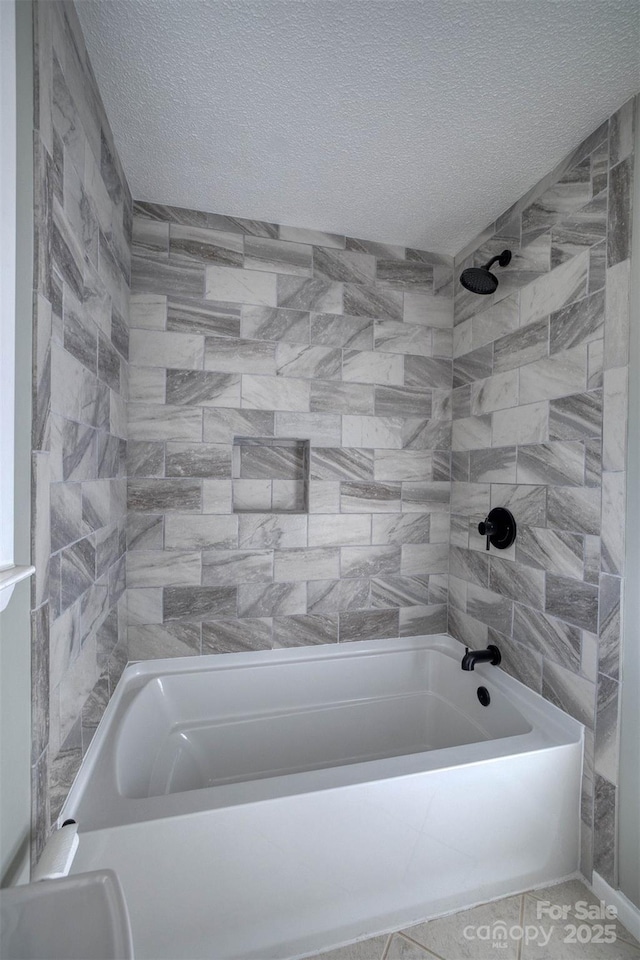 bathroom with tiled shower / bath and a textured ceiling