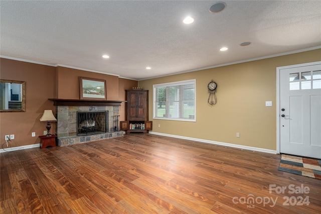 unfurnished living room featuring ornamental molding, a textured ceiling, a tile fireplace, and hardwood / wood-style floors