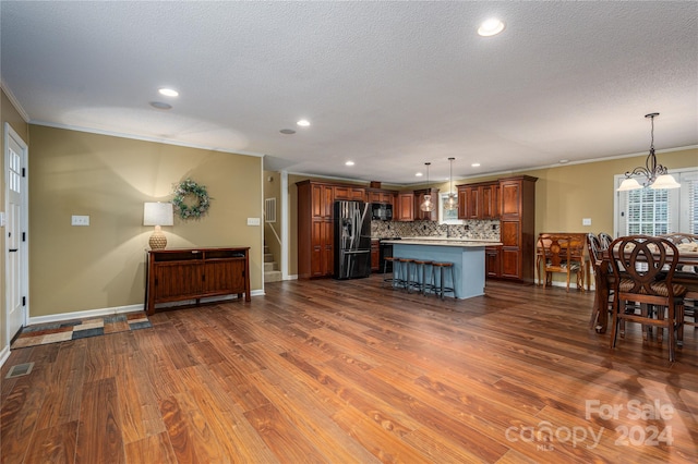 living room featuring a textured ceiling, ornamental molding, dark hardwood / wood-style flooring, and an inviting chandelier