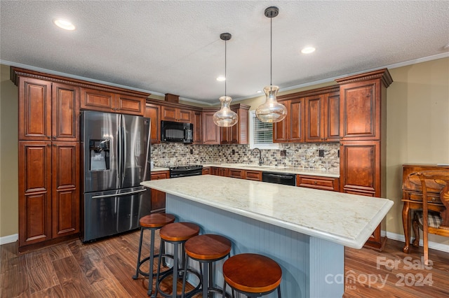 kitchen with a kitchen island, decorative light fixtures, dark wood-type flooring, black appliances, and crown molding