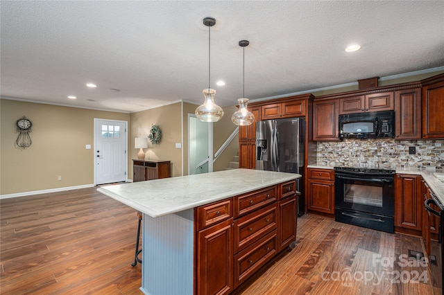 kitchen with a breakfast bar, a center island, dark wood-type flooring, black appliances, and decorative light fixtures