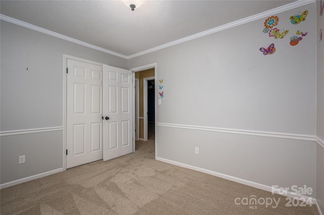 unfurnished bedroom with light colored carpet, a textured ceiling, and crown molding