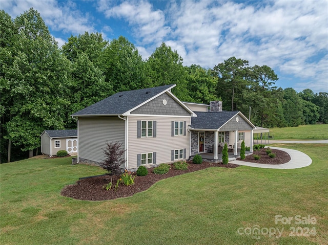 tri-level home featuring a front lawn, an outdoor structure, and covered porch