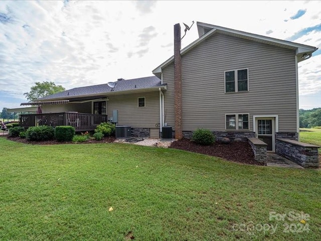 rear view of house with a lawn, cooling unit, and a wooden deck