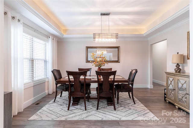 dining room featuring an inviting chandelier, a tray ceiling, light hardwood / wood-style flooring, and crown molding