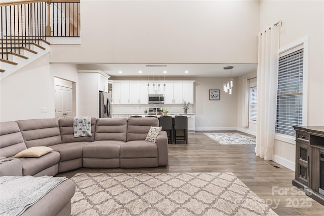 living room featuring a towering ceiling and light wood-type flooring