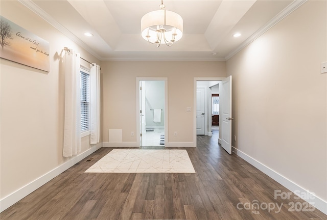 interior space with dark wood-type flooring, ornamental molding, a raised ceiling, and a notable chandelier