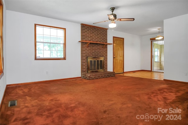 unfurnished living room featuring a fireplace, light carpet, brick wall, and ceiling fan