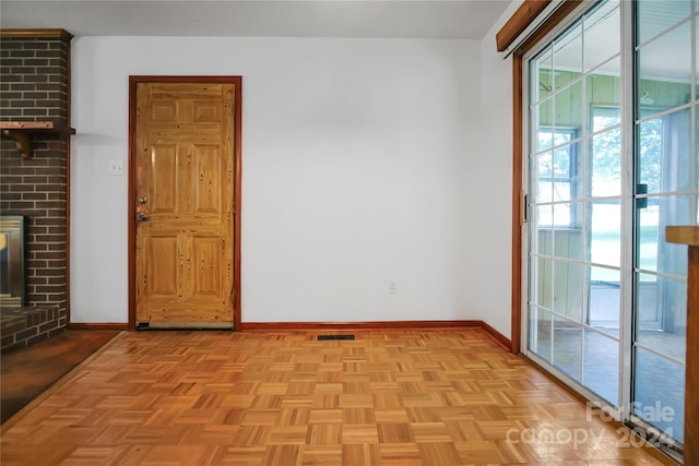 unfurnished room with brick wall, light parquet flooring, and a brick fireplace