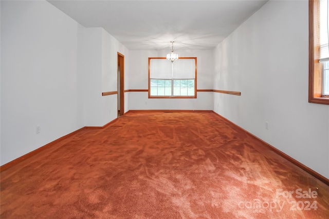 carpeted empty room with a chandelier