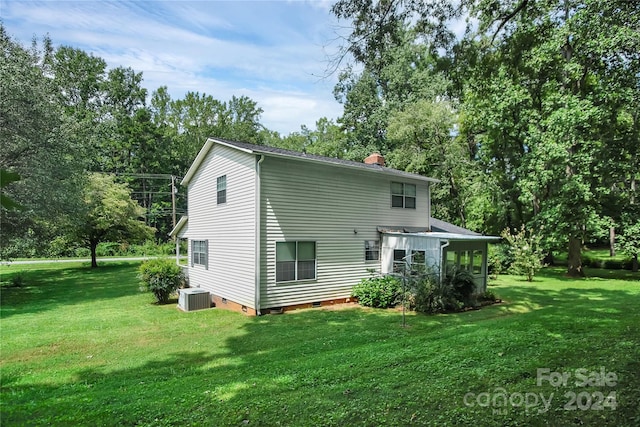 rear view of property featuring central AC unit and a yard