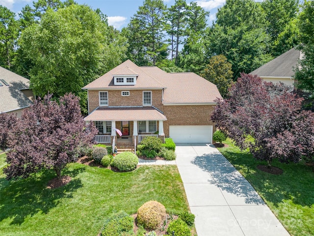 view of front of home featuring a porch, a front yard, and a garage