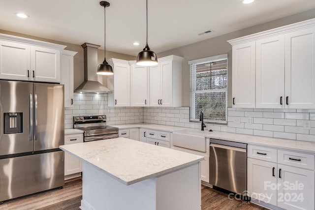 kitchen featuring white cabinetry, wall chimney range hood, stainless steel appliances, and sink