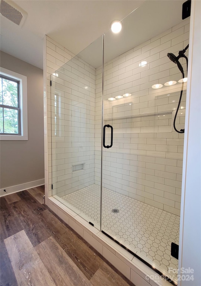 bathroom with a shower with door and hardwood / wood-style floors