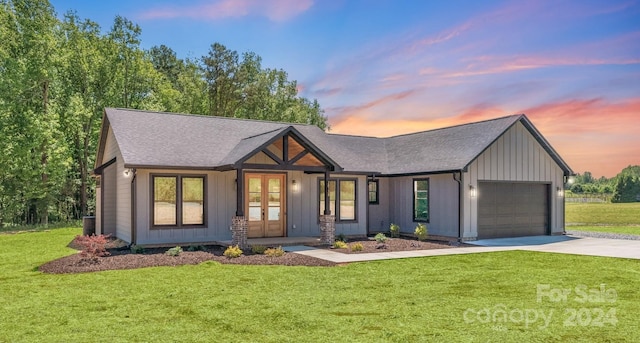 view of front of house with a garage, a yard, and french doors