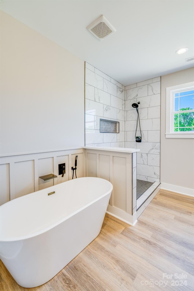 bathroom featuring plus walk in shower and hardwood / wood-style floors