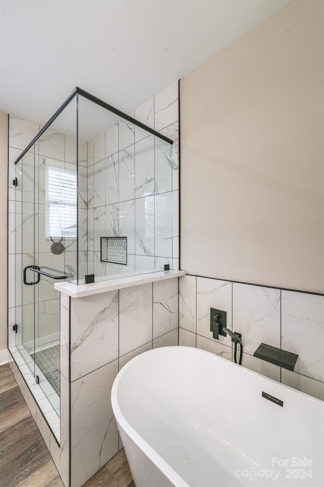 bathroom with tile walls, wood-type flooring, and shower with separate bathtub