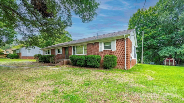 ranch-style home with a storage shed and a front yard