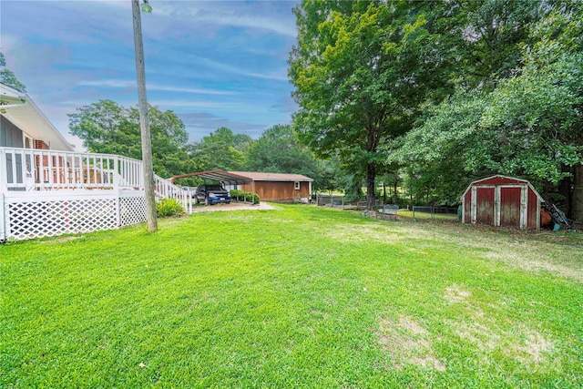 view of yard with a deck, a storage unit, and a carport