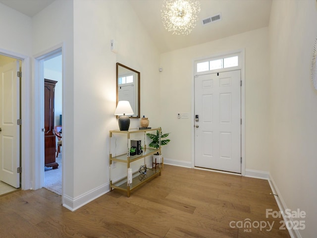 entrance foyer featuring vaulted ceiling, an inviting chandelier, and light wood-type flooring