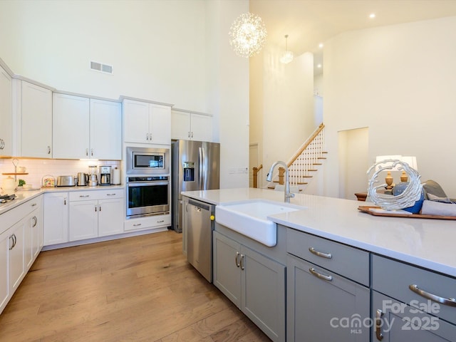 kitchen with pendant lighting, stainless steel appliances, sink, and white cabinets