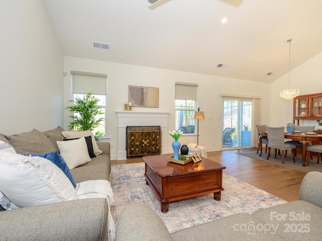 living room featuring an inviting chandelier, lofted ceiling, and light hardwood / wood-style floors