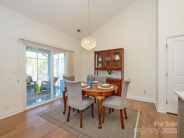 dining space featuring lofted ceiling, light hardwood / wood-style floors, and a notable chandelier