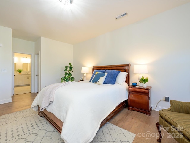 bedroom featuring ensuite bathroom and light hardwood / wood-style flooring