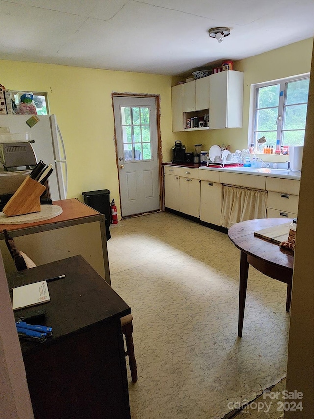 kitchen featuring white fridge and white cabinetry