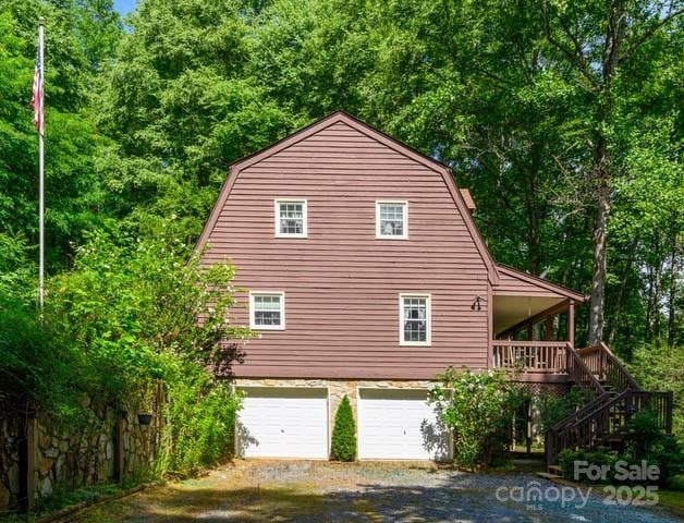 2767 Tanasee Gap Rd, Balsam Grove, NC 28708 - view of side of home with gravel driveway, a gambrel roof, stairway, and a garage