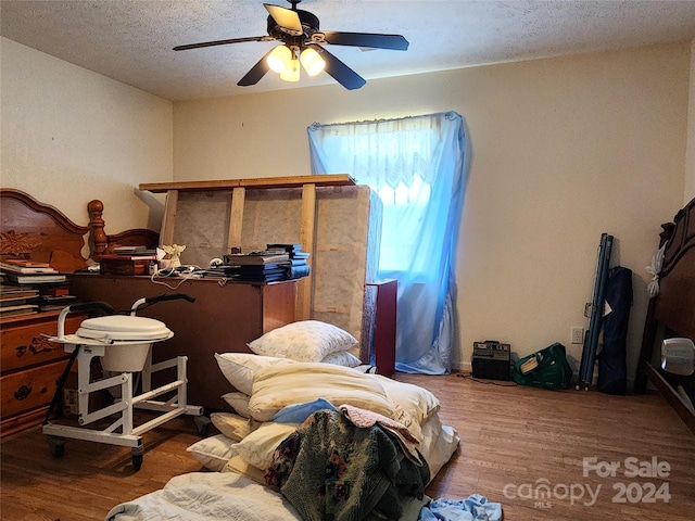 bedroom with ceiling fan, a textured ceiling, and hardwood / wood-style floors