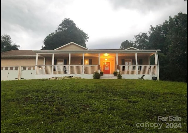 view of front facade with covered porch, a front yard, and a garage