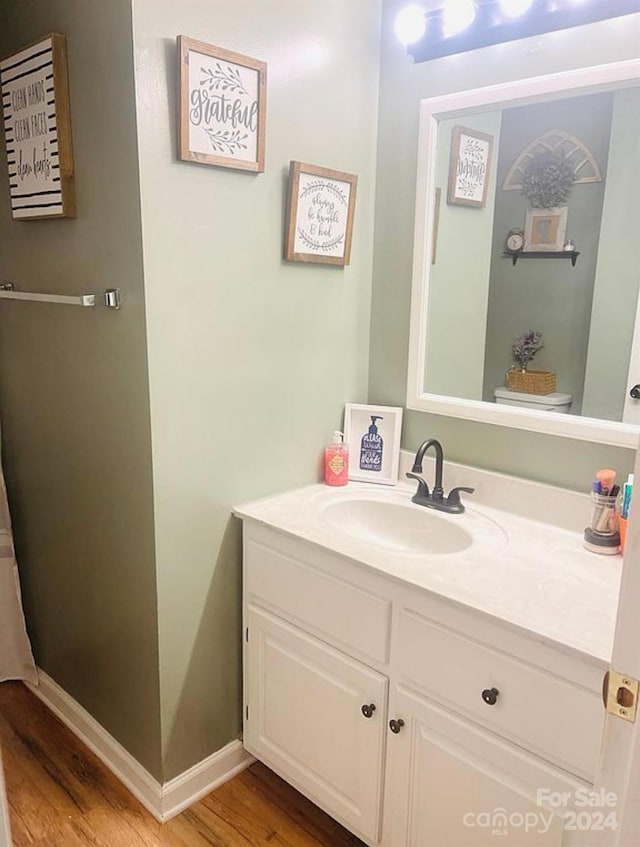 bathroom with toilet, vanity, and hardwood / wood-style flooring