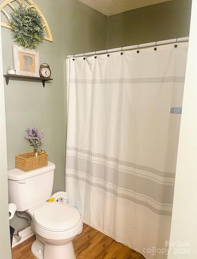 bathroom featuring toilet, a textured ceiling, and hardwood / wood-style flooring