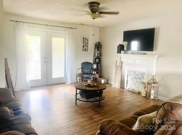 living room with a textured ceiling, ceiling fan, hardwood / wood-style floors, and french doors