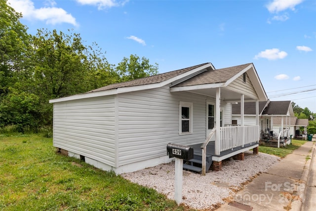 view of property exterior featuring covered porch and a yard