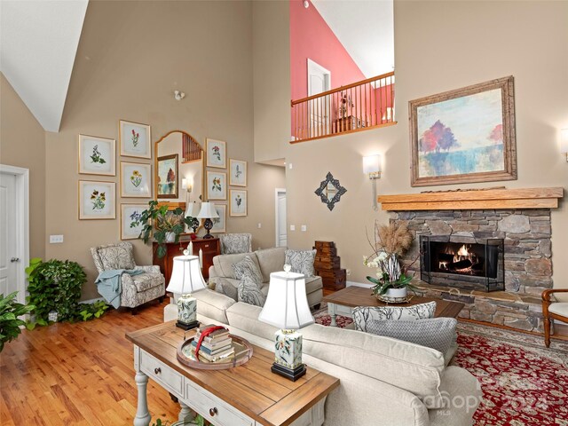 living room featuring high vaulted ceiling, a fireplace, and wood-type flooring