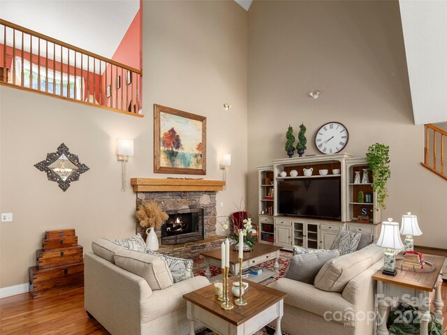 living room featuring a fireplace, hardwood / wood-style floors, and a towering ceiling