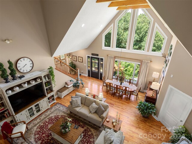 living room featuring beamed ceiling, wood-type flooring, and high vaulted ceiling