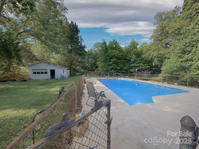 view of swimming pool featuring a garage, an outdoor structure, and a lawn