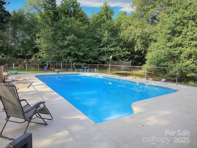 view of swimming pool with a patio and a trampoline