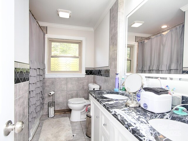 bathroom with tile patterned flooring, tile walls, vanity, ornamental molding, and toilet