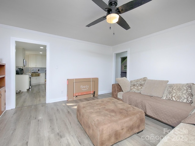 living room featuring ornamental molding, light hardwood / wood-style floors, and ceiling fan