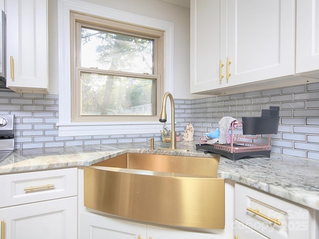 kitchen featuring white cabinetry, tasteful backsplash, sink, and light stone counters